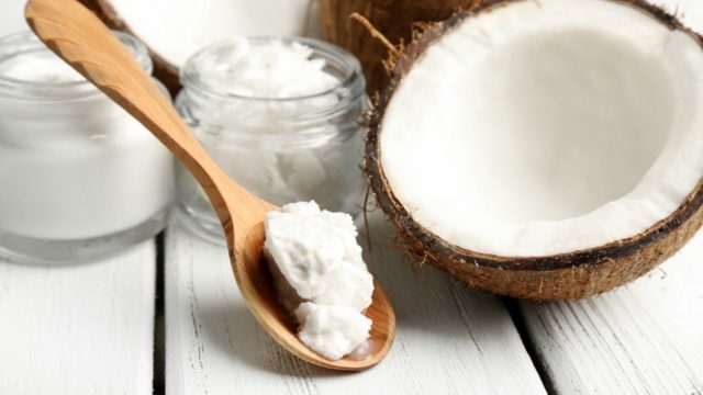Coconut with jars of coconut oil on wooden background