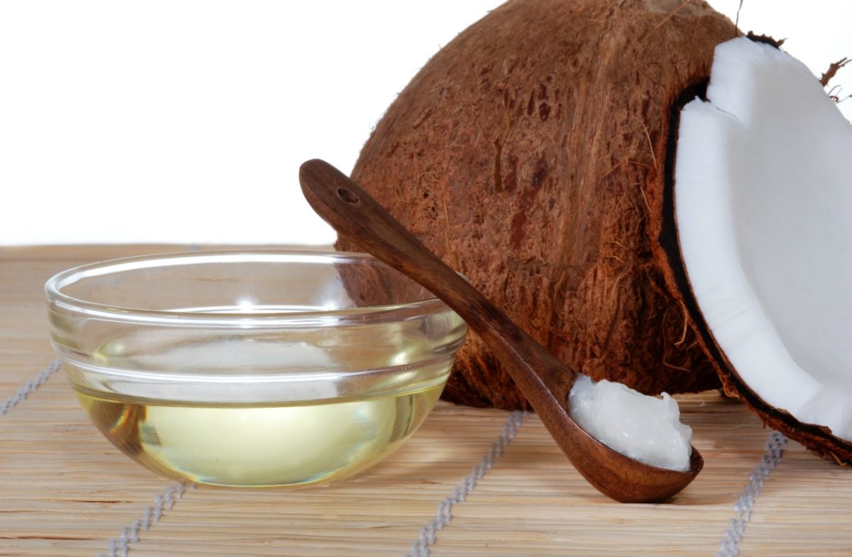Open coconut, coconut oil in a bowl with a spoon