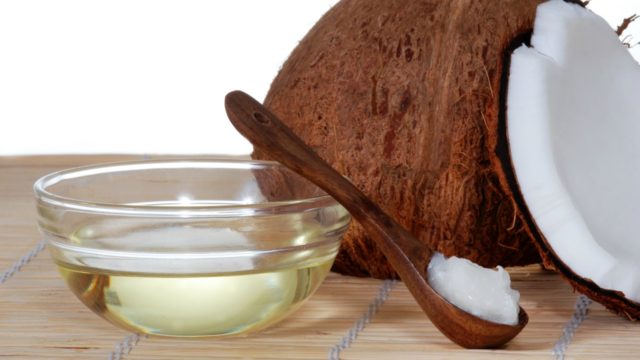 Open coconut, coconut oil in a bowl with a spoon