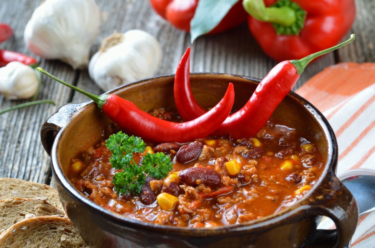 Bowl of chili with red chili peppers on top
