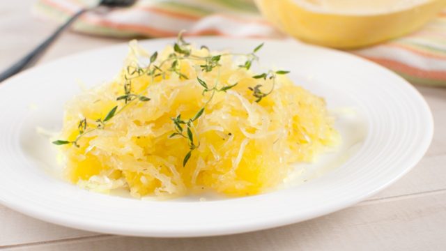 Cooked yellow spaghetti squash on white plate