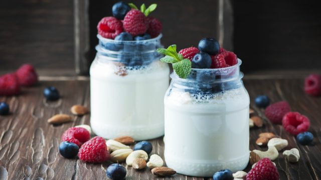 Two mason jars with milk and topped with fruit